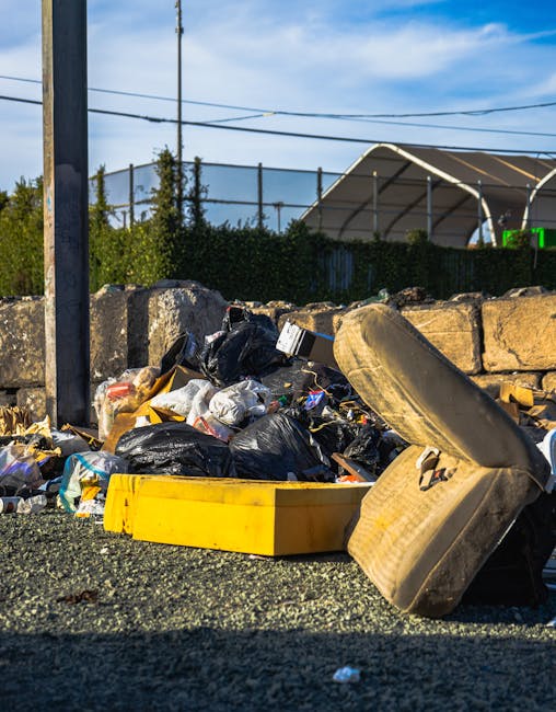 Photograph showing the rear side of a white commercial van parked on a street with three large blue plastic rubbish bags placed alongside it on the pavement. The bags appear to be filled with waste ma